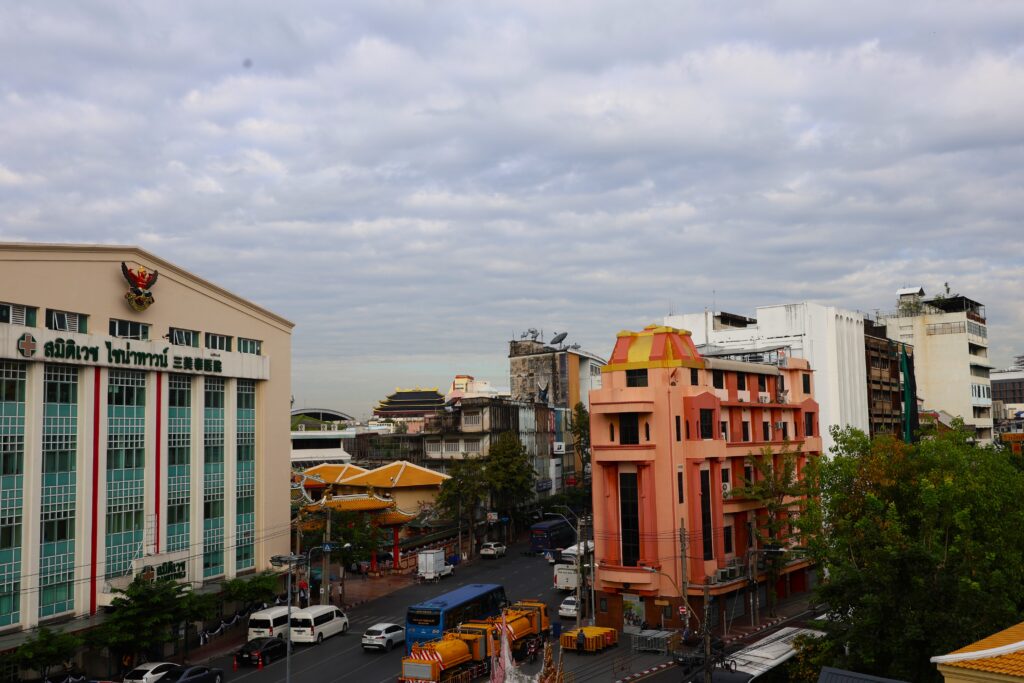 Widok z okolic świątyni Złotego Buddy w stronę bramy Chinatown pokazuje Bangkok takim, jaki jest naprawdę — chaotyczny, wielowarstwowy i pełen kontrastów między sacrum, codziennością i nowoczesnym miastem.