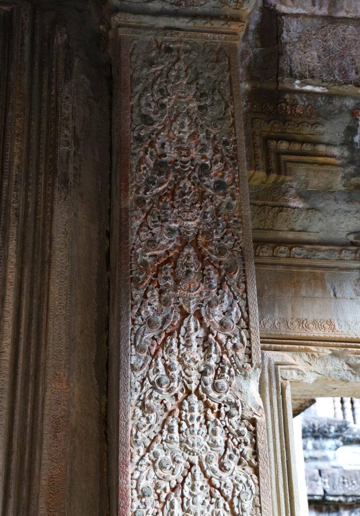 Misternie rzeźbiony filar świątyni Angkor z bogatymi, khmerskimi ornamentami roślinnymi i postaciami.