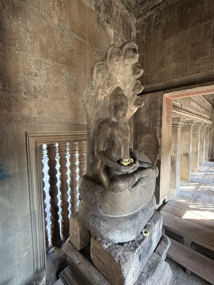 Kamienna statua Buddy siedzącego na wężu Naga we wnętrzu świątyni Angkor.